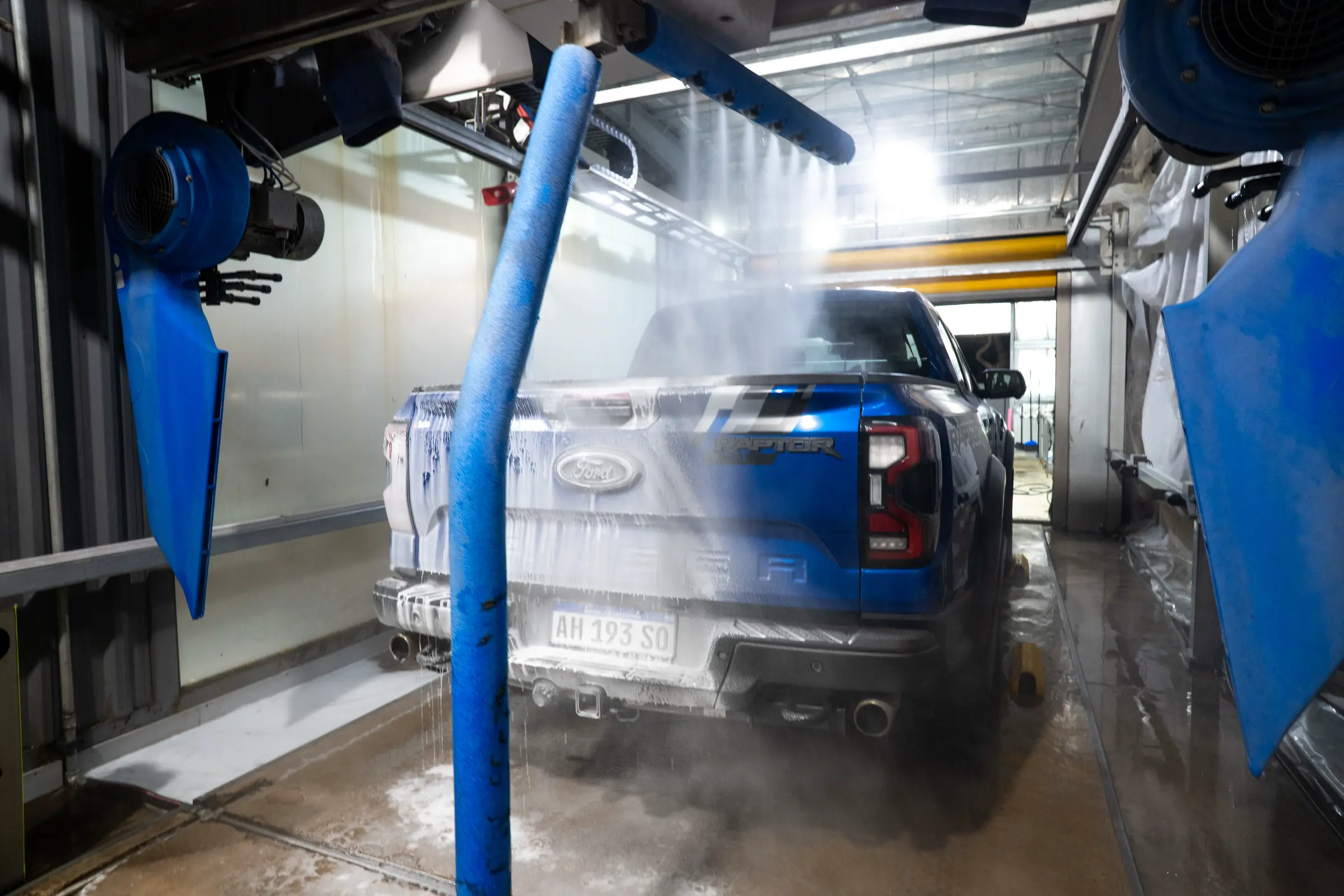 Brazos automáticos lavando una camioneta con agua a presión